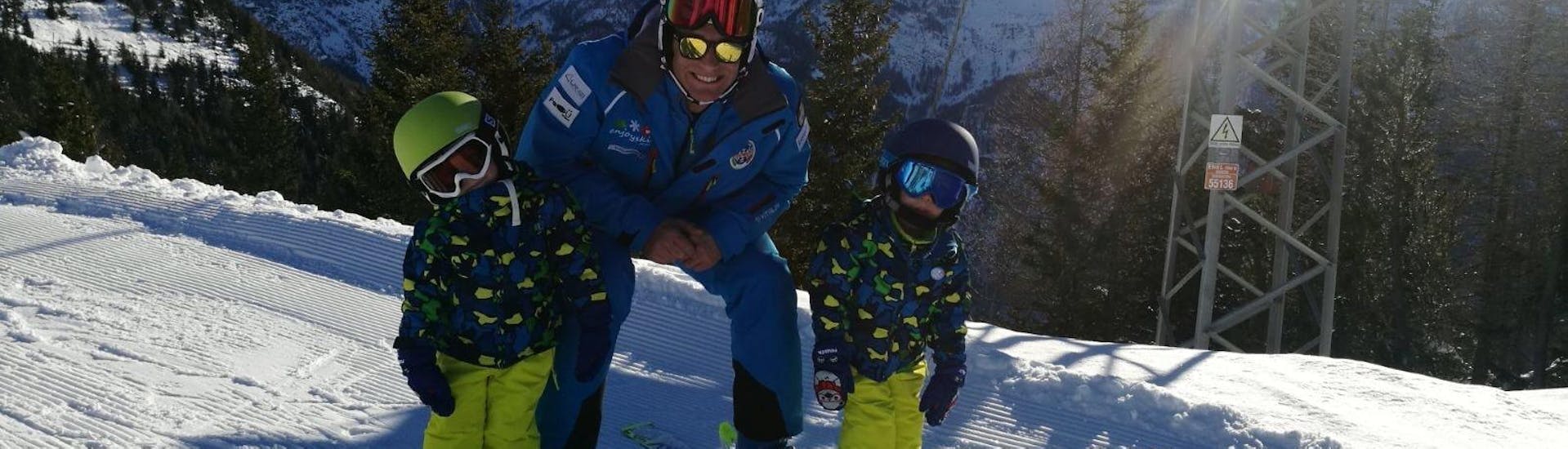Der Skilehrer lächelt mit zwei Kindern während eines privaten Skikurses für Kinder der Enjoyski School Valmalenco - für alle Levels.