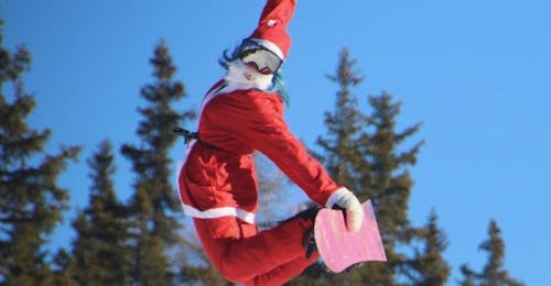 Private Snowboardkurse für Kinder und Erwachsene für alle Levels mit Enjoyski School Valmalenco Ein Snowboardlehrer im Weihnachtsmannkostüm springt in Valmalenco nach einem Snowboard-Privatkurs für Kinder und Erwachsene  in die Luft - für alle Levels.