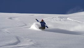 Uno snowboarder scende sulle piste durante le lezioni di snowboard per ragazzi di tutti i livelli con la scuola di sci Neustift Olympia sul ghiacciaio dello Stubai.