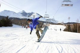 During the Snowboard Instructor Private - All Levels & Ages, a snowboarder is having fun with his experienced instructor from the ski school Ternavski Snow Academy Tatranska Lomnica while performing new tricks.