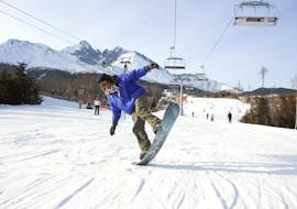 Im Rahmen des Angebots Snowboard Privatlehrer - Alle Levels & Altersgruppen hat ein Snowboarder mit seinem erfahrenen Lehrer von der Skischule Ternavski Snow Academy Tatranska Lomnica viel Spaß bei der Ausführung neuer Tricks.
