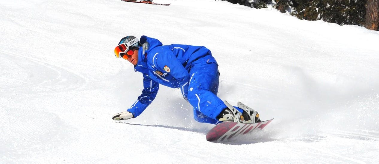Le Lezioni di snowboard per bambini e adulti - Tutti i livelli della scuola di sci Folgarida Dimaro Ski School si stanno svolgendo, il maestro di snowboard mostra la tecnica sulle piste della Val di Sole.