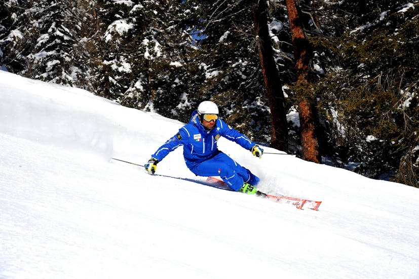 Le Lezioni private di sci per bambini - Tutte le età della scuola di sci Folgarida Dimaro Ski School si stanno svolgendo, il maestro di snowboard mostra la tecnica sulle piste della Val di Sole.