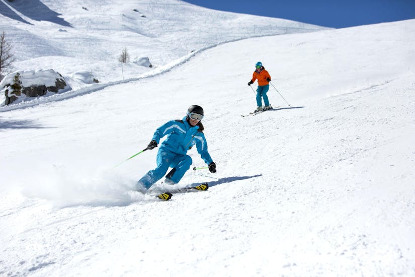 Un esquiador baja por una pista nevada detrás de su instructor de la escuela de esquí ESI Font Romeu durante una clase de esquí para adultos - Vacaciones - Todos los niveles.