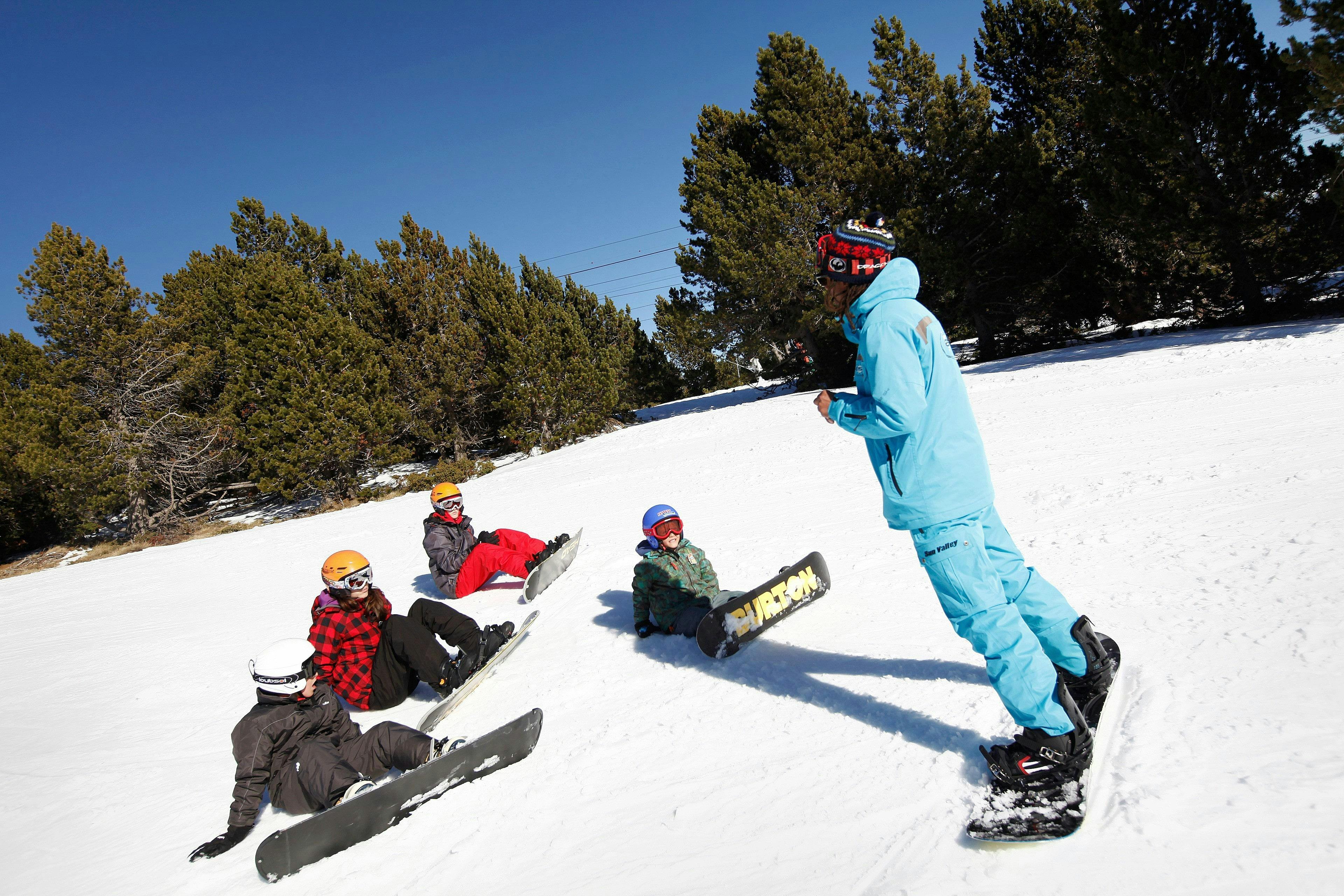 Cours de snowboard (dès 8 ans) pour Tous niveaux avec ESI Font Romeu - École de ski Un moniteur de snowboard de l'école de ski ESI Font Romeu instruit un groupe de snowboardeurs pendant leur Cours de snowboard pour Enfants & Adultes - Vacances.