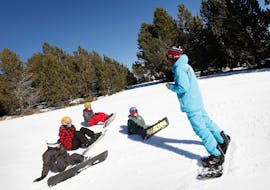 Ein Snowboardlehrer der Skischule ESI Font Romeu unterrichtet eine Gruppe von Snowboardern während ihres Snowboardunterrichts für Kinder & Erwachsene - Ferien.