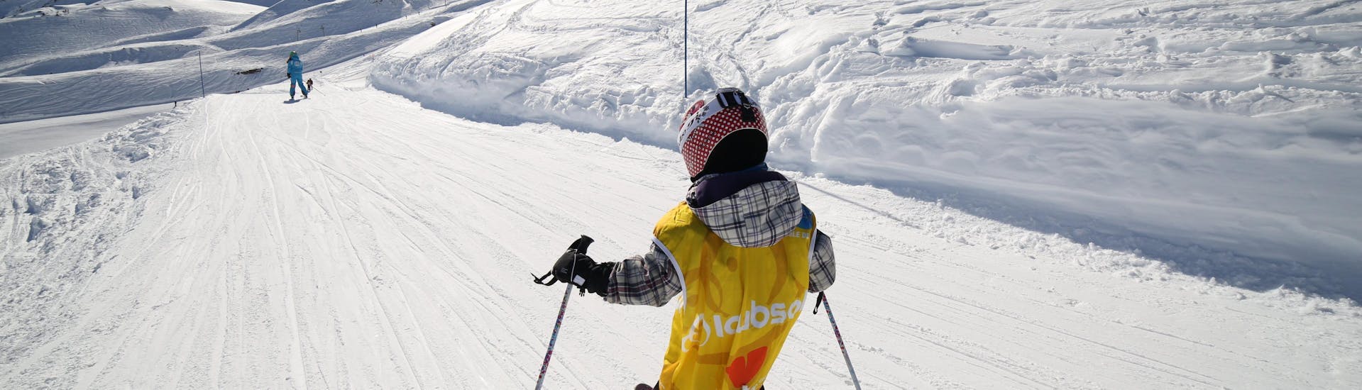 Un pequeño esquiador baja por una nevada pista de esquí durante una clase particular para niños - Vacaciones con la escuela de esquí ESI Font Romeu.