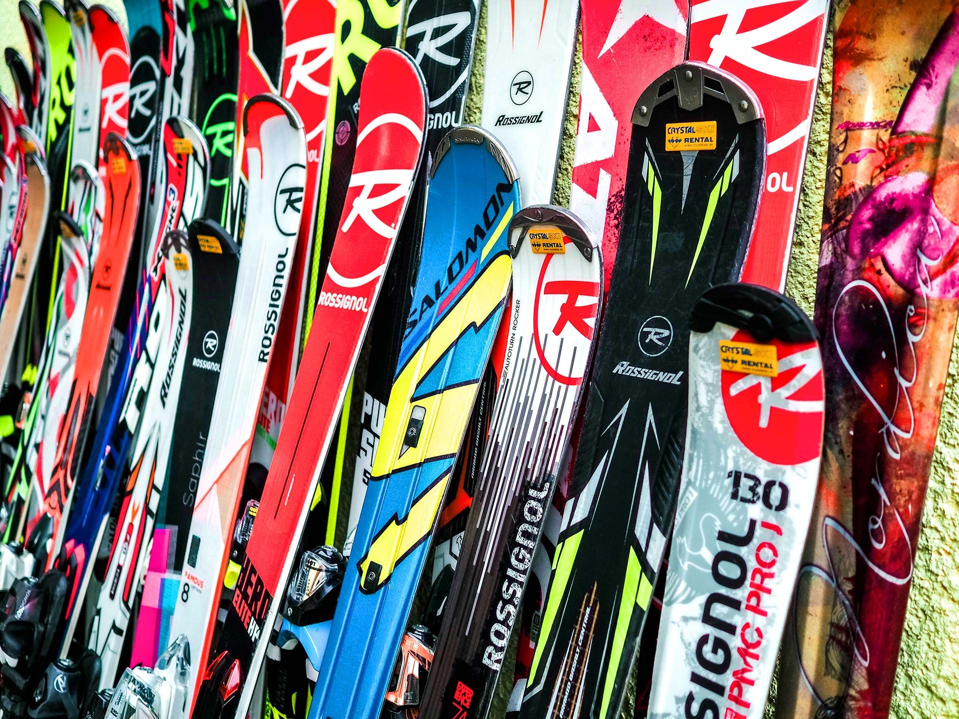 Lots of different Skis leaning on a wall